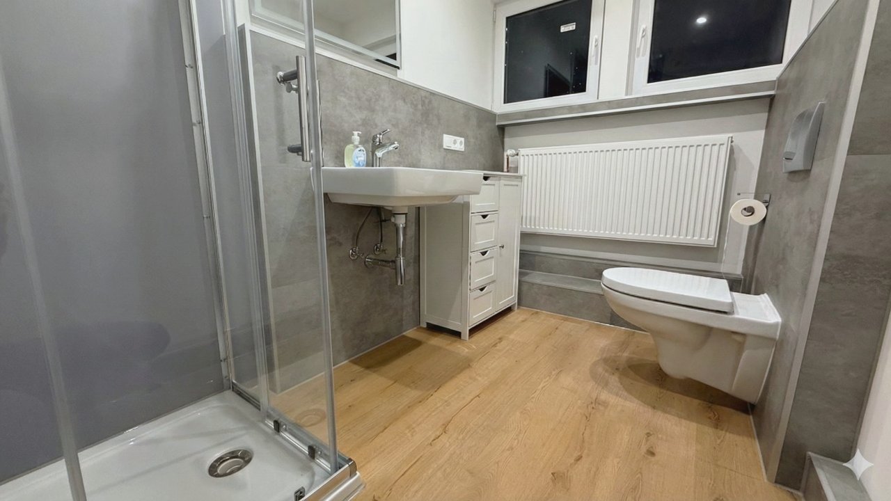 Saniertes Bad mit Dusche, Waschbecken und Fenster