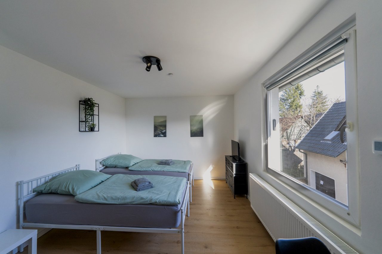 Helles Doppelzimmer mit zwei Betten, Sonnenlicht fällt durch das große Fenster