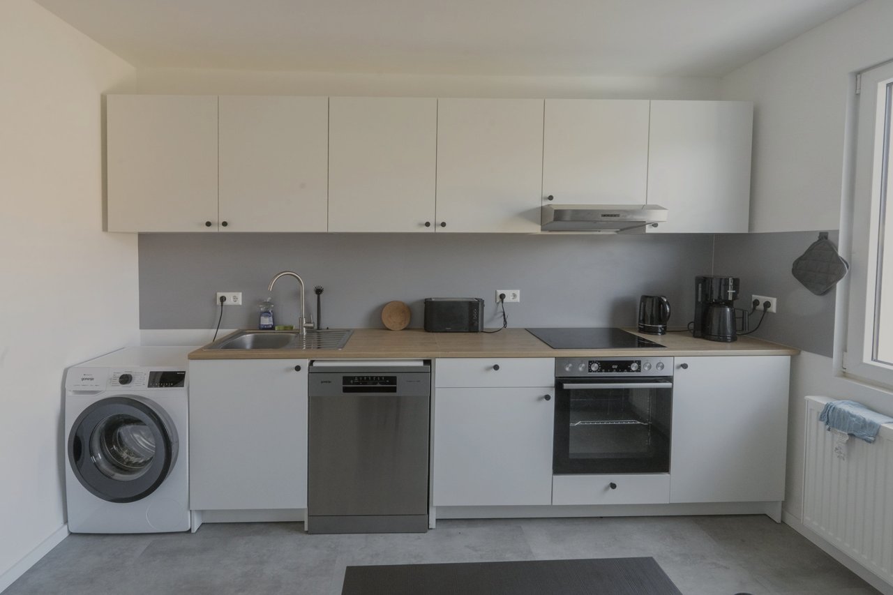 Küche mit Holzarbeitsplatte, Backofen, Spülmaschine und Waschmaschine
